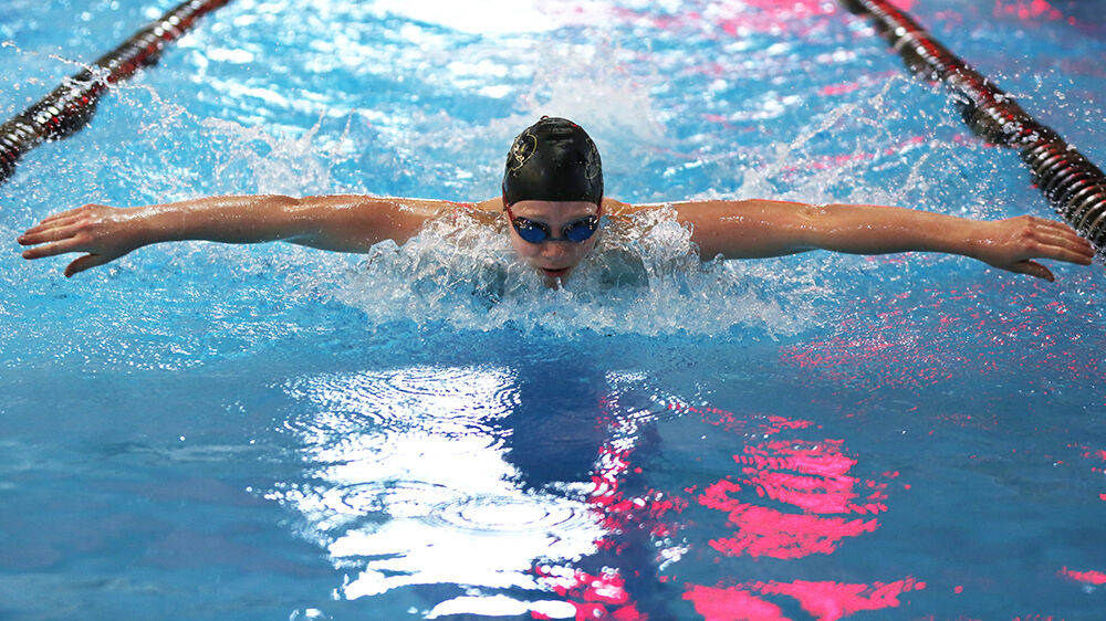 Makenna Lambert looks up to take a breath during the first half of her butterfly leg